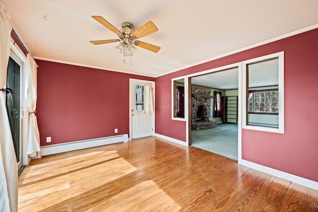 spare room featuring wood finished floors, baseboards, baseboard heating, and ornamental molding