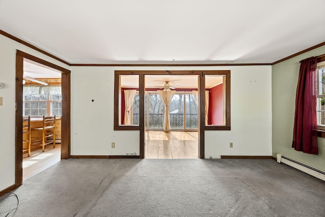 carpeted spare room with a baseboard heating unit, crown molding, baseboards, and a ceiling fan