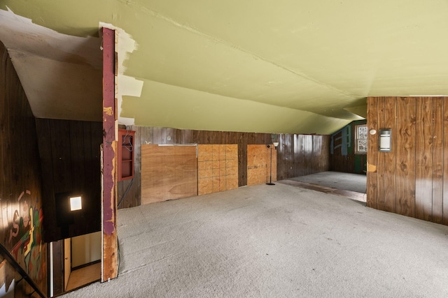 additional living space with wooden walls, carpet flooring, and vaulted ceiling