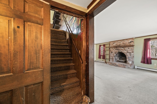 stairs featuring baseboard heating, a fireplace, and carpet floors