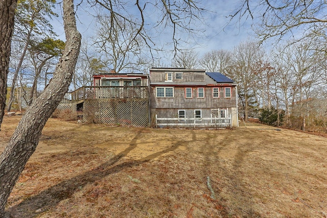 view of front facade featuring roof mounted solar panels, a deck, and a front lawn