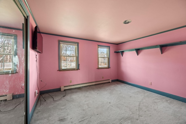 carpeted spare room featuring a baseboard heating unit, crown molding, and baseboards