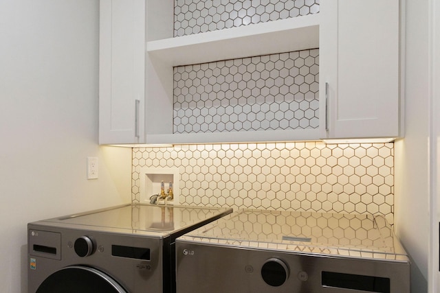 laundry room with washing machine and clothes dryer and cabinet space