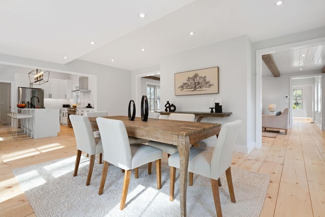 dining space featuring light wood finished floors, beamed ceiling, an inviting chandelier, and recessed lighting