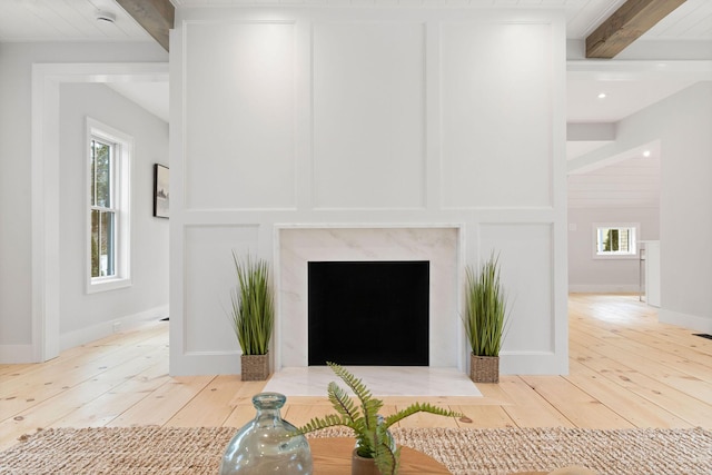 details featuring baseboards, a decorative wall, beam ceiling, and wood finished floors