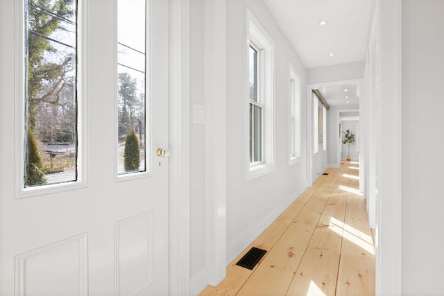 hallway with recessed lighting, light wood-type flooring, visible vents, and baseboards