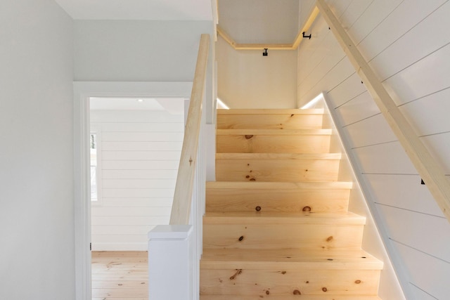 stairs featuring wood walls and wood finished floors