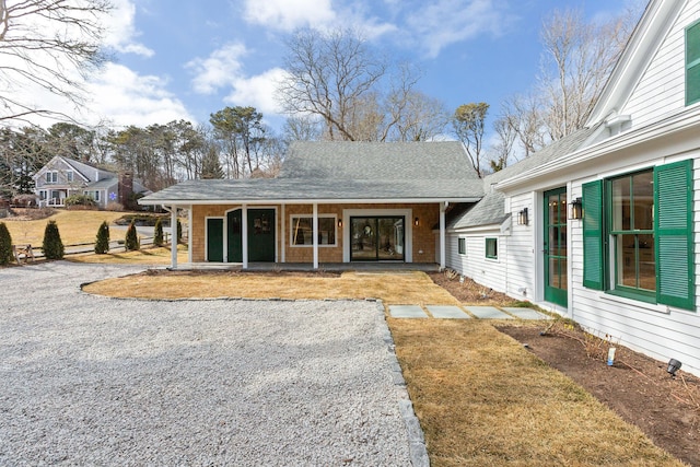 view of front facade featuring driveway and roof with shingles