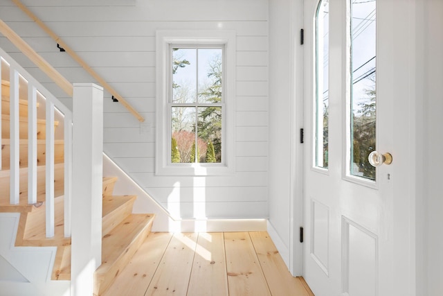 doorway to outside with a healthy amount of sunlight, wood walls, stairway, and hardwood / wood-style floors