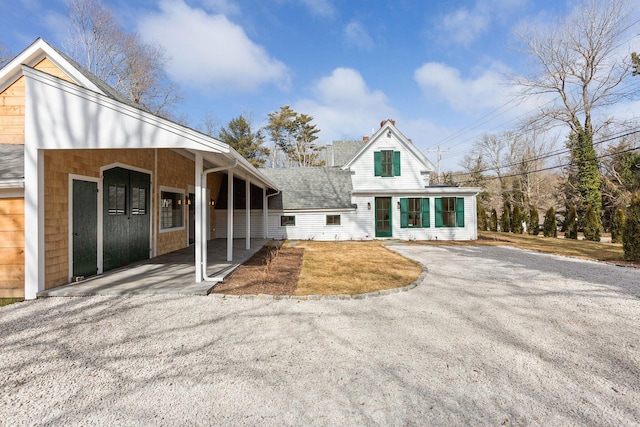 view of front of house with driveway, a shingled roof, and a sunroom