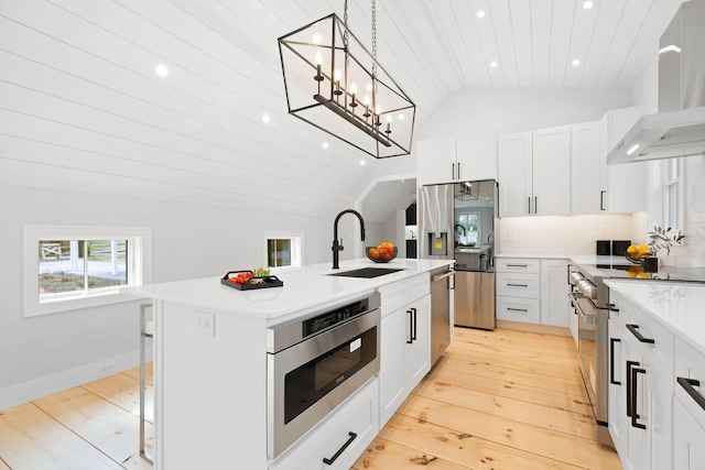 kitchen featuring stainless steel appliances, backsplash, vaulted ceiling, a sink, and wall chimney range hood