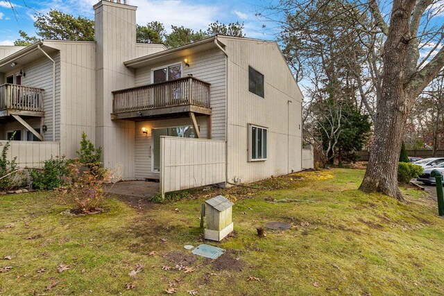 back of house featuring a balcony and a lawn