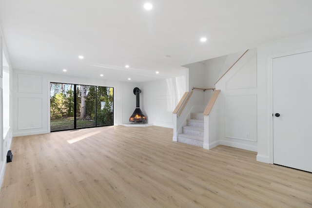 unfurnished living room with light wood-type flooring and a wood stove