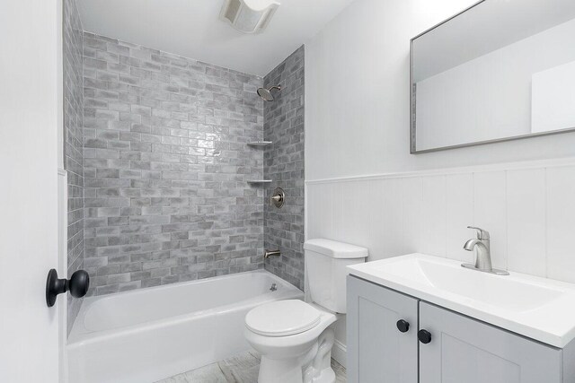 full bathroom featuring tiled shower / bath combo, toilet, and vanity