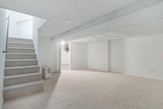 basement with a paneled ceiling and carpet flooring