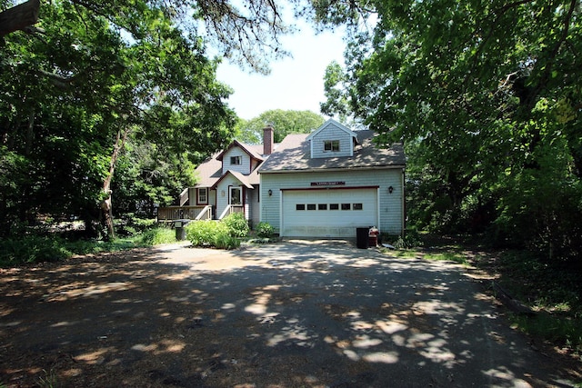 view of front facade with aphalt driveway, an attached garage, and a chimney