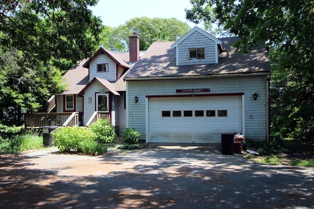 view of front facade featuring an attached garage, a chimney, and driveway