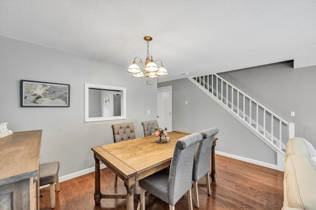 dining space featuring hardwood / wood-style floors, an inviting chandelier, and a textured ceiling