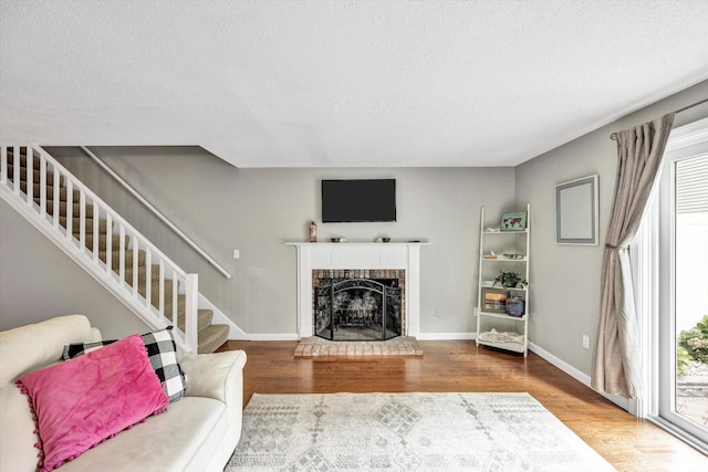 living room with wood-type flooring, a textured ceiling, and a fireplace