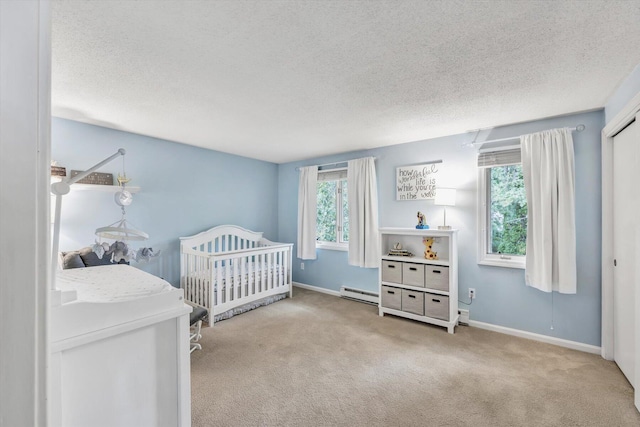 bedroom featuring light colored carpet, a baseboard radiator, a crib, and a textured ceiling