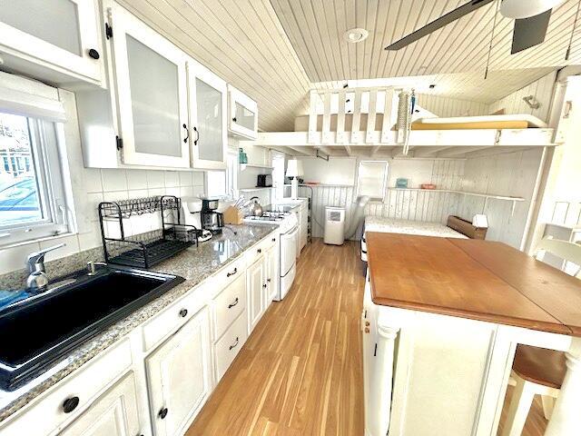 kitchen with wooden ceiling, white cabinets, gas range gas stove, and dark stone countertops