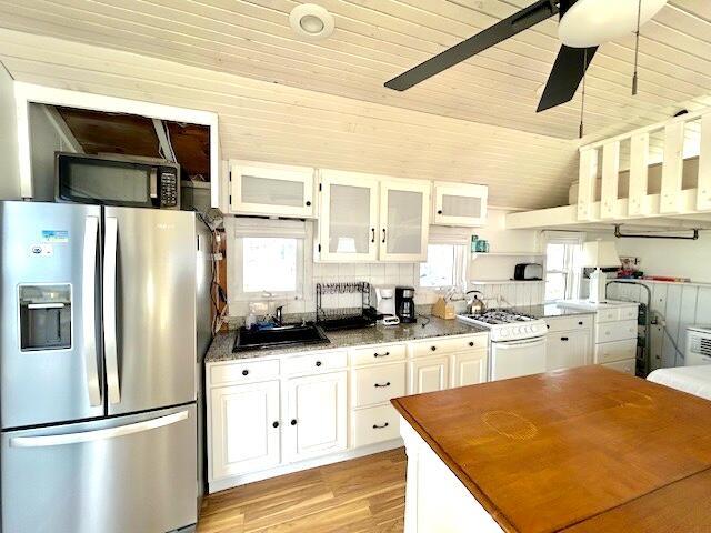 kitchen featuring sink, white cabinetry, stainless steel fridge with ice dispenser, wood ceiling, and white gas stove