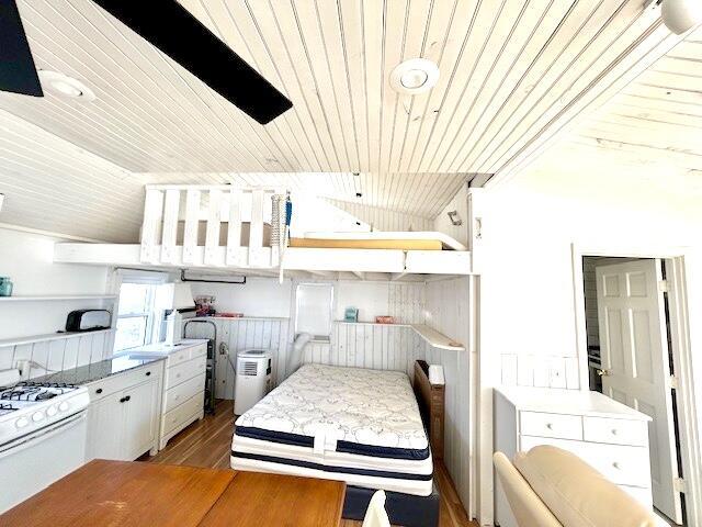 interior space featuring dark wood-type flooring, white range with gas stovetop, white cabinetry, and wood ceiling