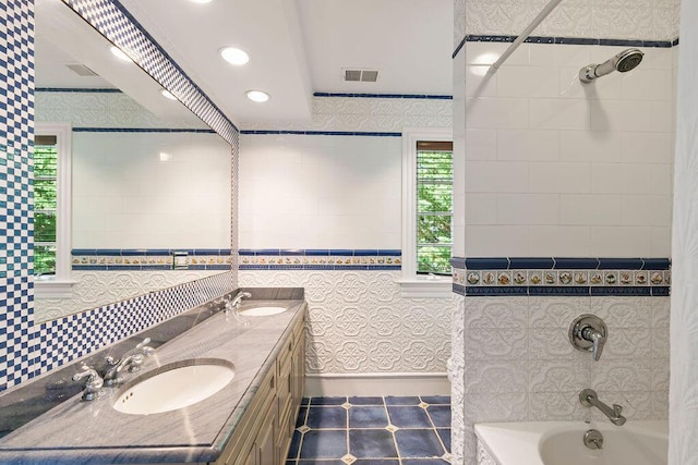 bathroom with plenty of natural light, tiled shower / bath, tile patterned flooring, and vanity