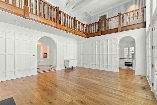 unfurnished living room featuring a fireplace, light hardwood / wood-style flooring, and a towering ceiling