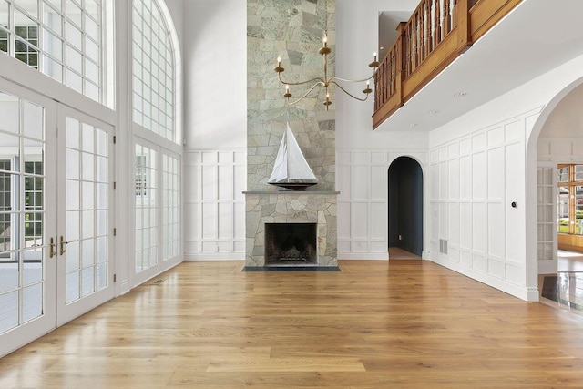 unfurnished living room with a fireplace, light hardwood / wood-style floors, and a towering ceiling