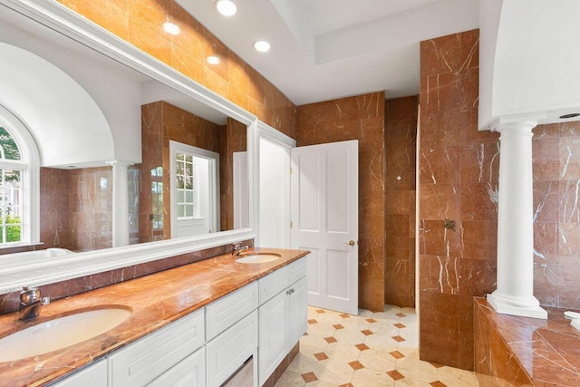 bathroom featuring vanity, ornate columns, and tile walls