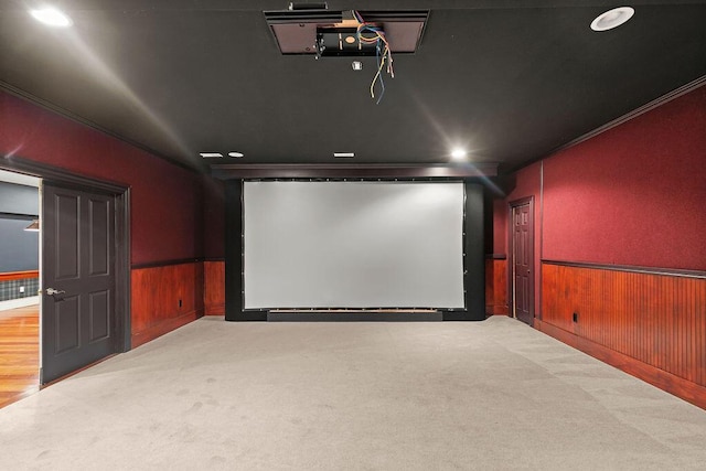 carpeted home theater with crown molding and wood walls