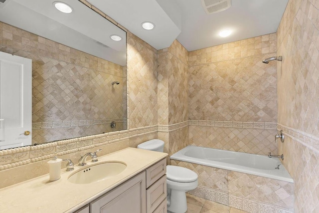 full bathroom featuring tiled shower / bath, tile patterned flooring, vanity, tile walls, and toilet