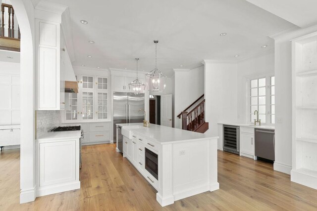 kitchen featuring built in appliances, white cabinetry, and a kitchen island with sink