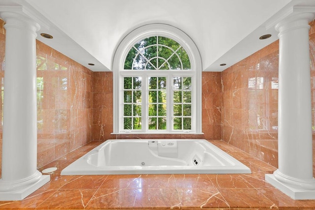 bathroom with ornate columns, a wealth of natural light, tile walls, and tiled bath