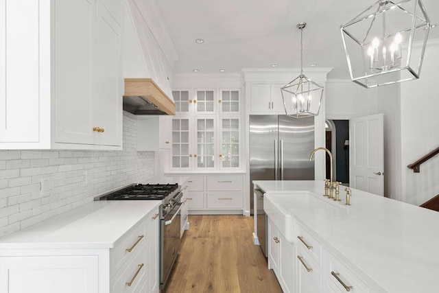 kitchen featuring pendant lighting, tasteful backsplash, white cabinetry, an island with sink, and high end appliances