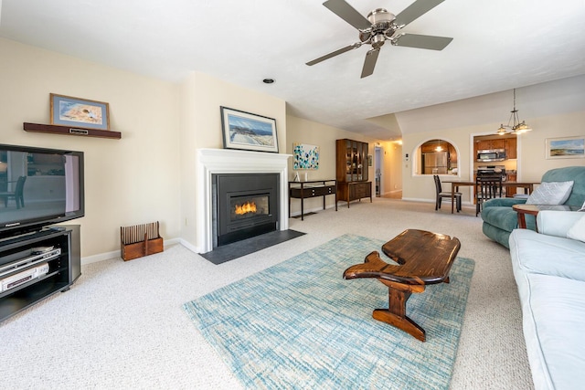 12 Kettle Ln, Mashpee, MA 02649 - carpeted living room featuring a fireplace with flush hearth, baseboards, arched walkways, and ceiling fan