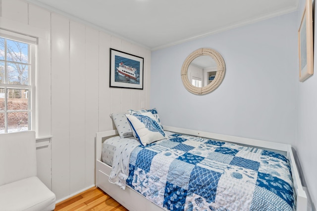 bedroom with multiple windows, hardwood / wood-style flooring, and ornamental molding