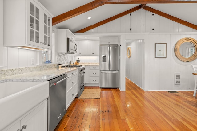 kitchen with white cabinets, stainless steel appliances, and vaulted ceiling with beams