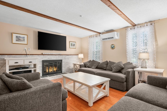 65 Hadrada Ln, Centerville, MA 02632 - living area with a wall mounted air conditioner, beamed ceiling, light wood-style floors, a fireplace, and a textured ceiling