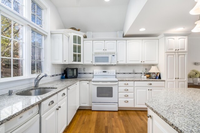 kitchen featuring white appliances, decorative backsplash, white cabinets, sink, and vaulted ceiling