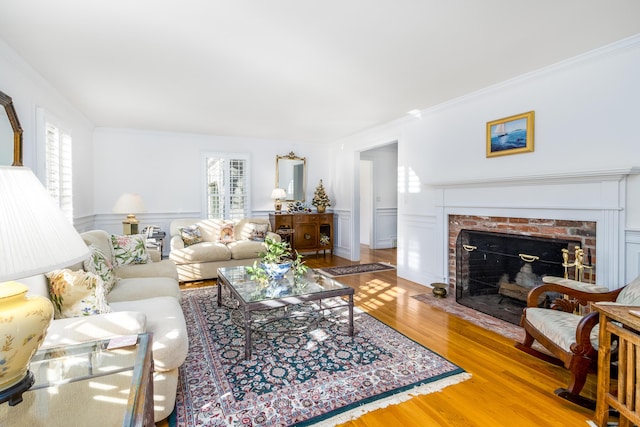 living room with a healthy amount of sunlight, crown molding, a fireplace, and wood-type flooring