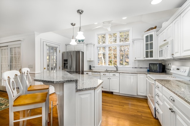 kitchen with white appliances, pendant lighting, white cabinets, and light stone counters