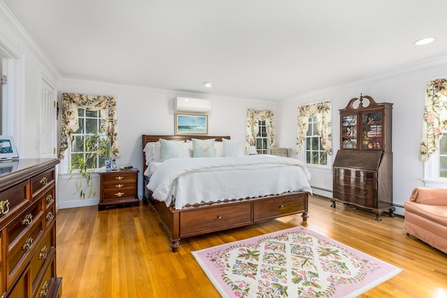 bedroom featuring wood-type flooring, a baseboard heating unit, ornamental molding, and a wall unit AC