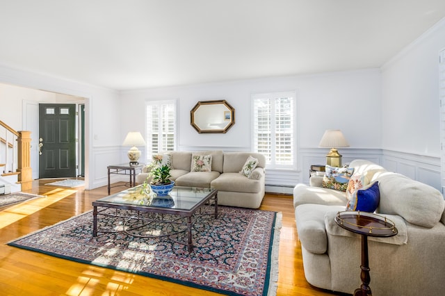 living room with a baseboard radiator, light wood-type flooring, and ornamental molding