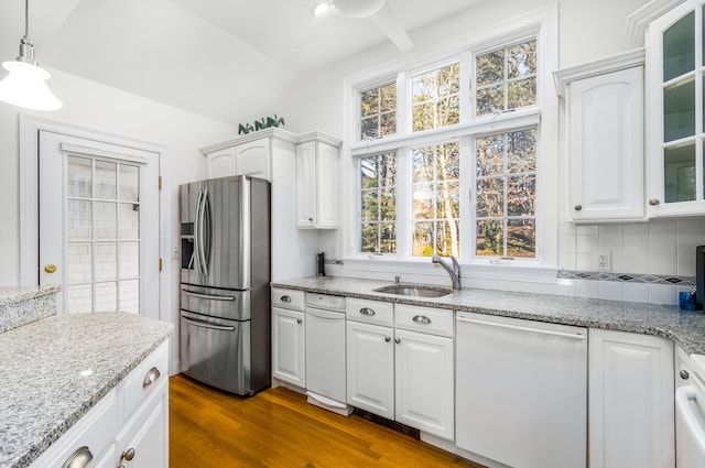 kitchen with white cabinets, sink, hanging light fixtures, stainless steel fridge, and white dishwasher