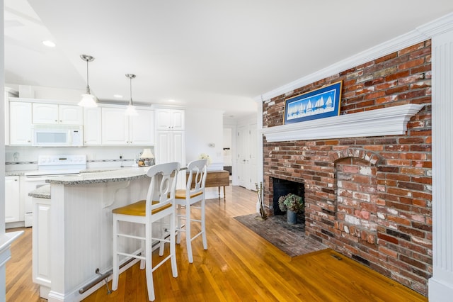 kitchen with white cabinetry, white appliances, hanging light fixtures, and light stone counters