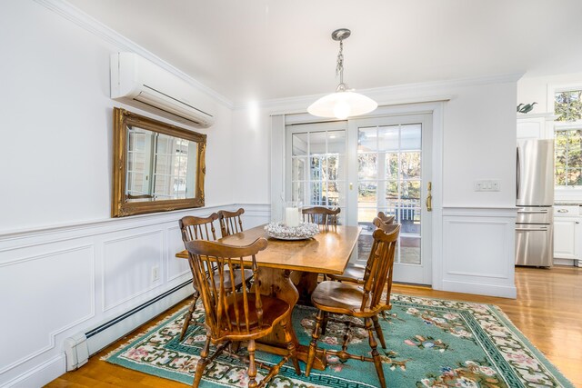 dining space featuring baseboard heating, light hardwood / wood-style floors, an AC wall unit, and ornamental molding