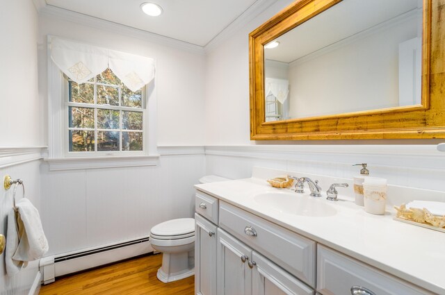 bathroom featuring wood-type flooring, baseboard heating, crown molding, toilet, and vanity