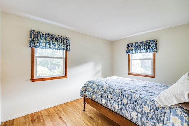 bedroom with multiple windows and hardwood / wood-style flooring